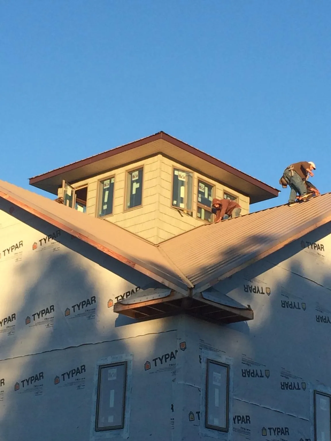 Roofers working around a rooftop cupola on a new metal roof at sunset — Roof Waterproofing in Portland by Roofing Brothers